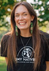 A  smiling woman with large earrings wearing a black t-shirt